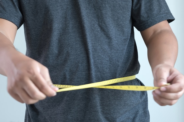 hombre comprobando cinta de medida de cintura de forma de cuerpo de cintura