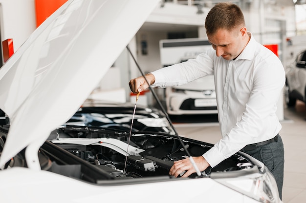 Hombre comprueba la presencia de aceite en el primer plano del automóvil