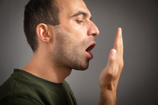 El hombre comprueba su aliento con la mano El concepto de halitosis