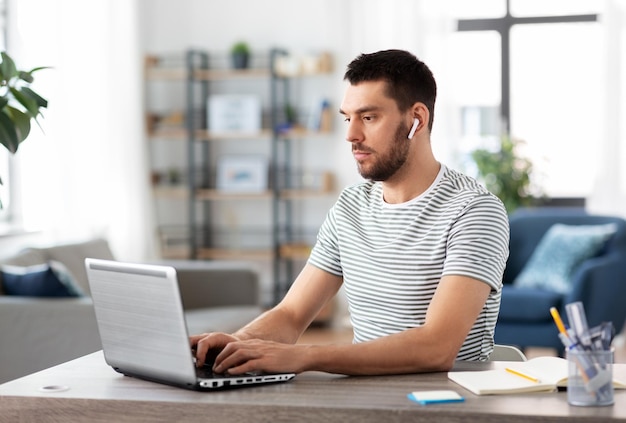 hombre con computadora portátil y auriculares en la oficina de casa