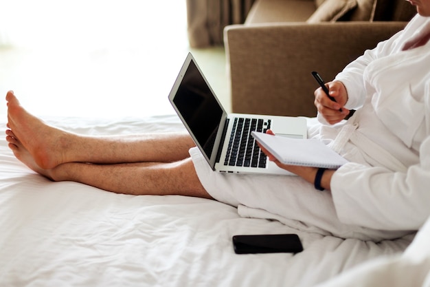 Un hombre con una computadora portátil en la cama el hombre en el dormitorio está acostado en una cama con una computadora en su regazo y ...