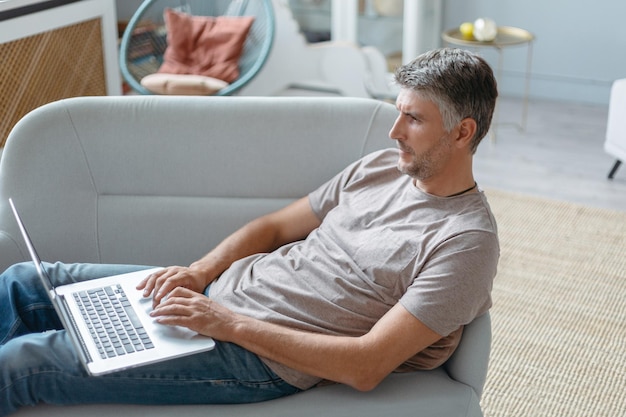 El hombre con una computadora portátil descansa en su sala de estar