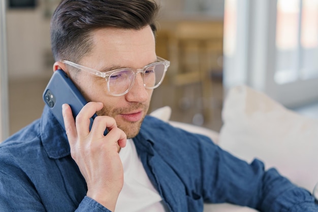 Un hombre concentrado conversa en un teléfono inteligente su expresión es una de comunicación atenta