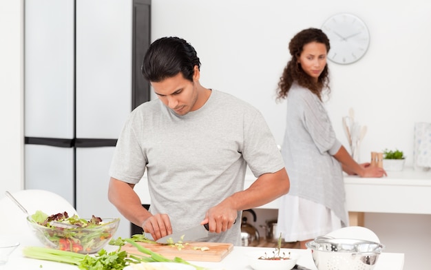 Hombre concentrado cortar verduras con su novia