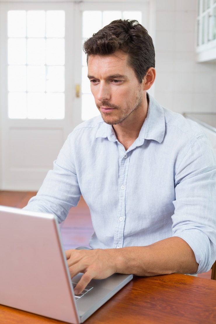 Foto hombre concentrado usando la computadora portátil en la mesa