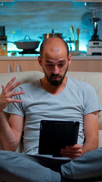 Hombre concentrado con videollamada de reunión en línea en tablet PC