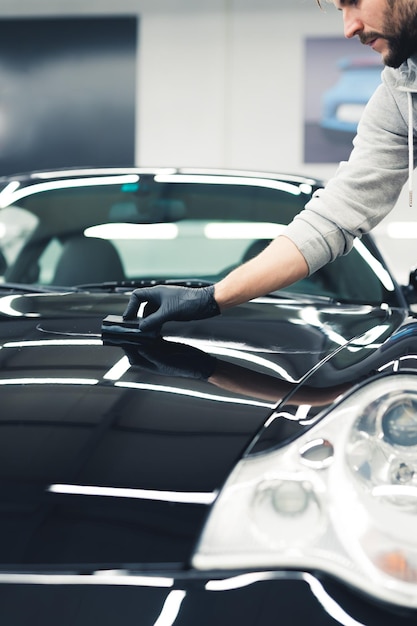 Hombre de concepto de revestimiento de cerámica que hace servicios de detalle de automóviles y cubre el capó o el capó del automóvil con un