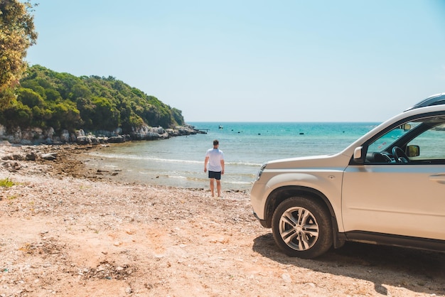 Hombre de concepto de viaje en coche en la playa de verano mirando al mar