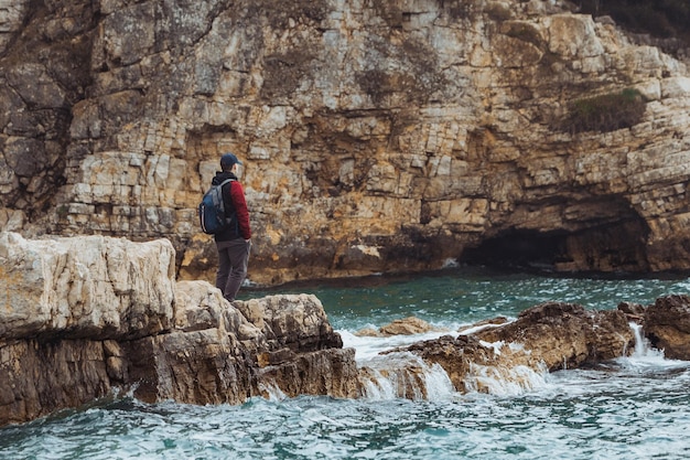 Hombre de concepto de viaje por mar en el acantilado con un clima ventoso tormentoso