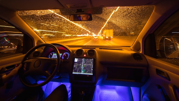 El hombre conduce el coche en la ciudad de noche. Gran angular