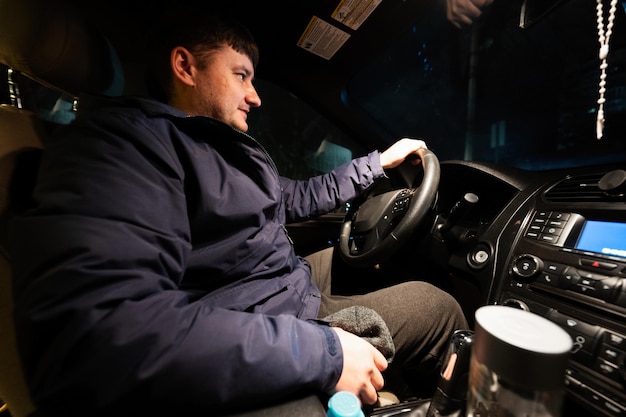 Hombre conduciendo un coche en la carretera por la noche