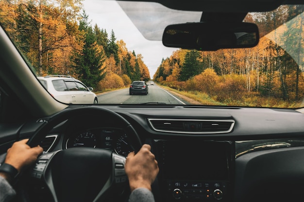 Hombre conduciendo un coche por la carretera rural en otoño