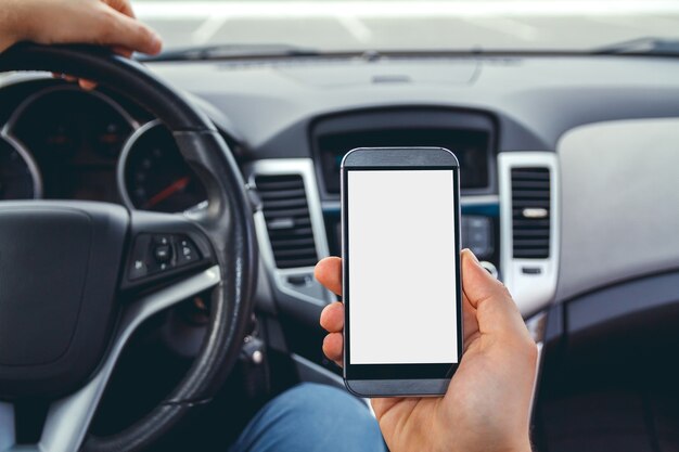 Hombre conduciendo un coche con un teléfono en la mano