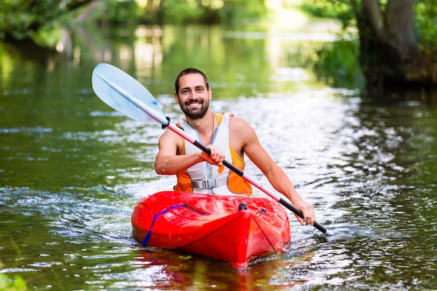 hombre conduciendo con kayak en el río bosque