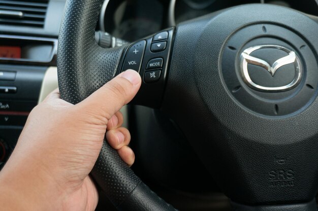 Hombre conduciendo manos presionando el botón en el volante en el concepto de conducción de seguridad de enfoque selectivo del automóvil