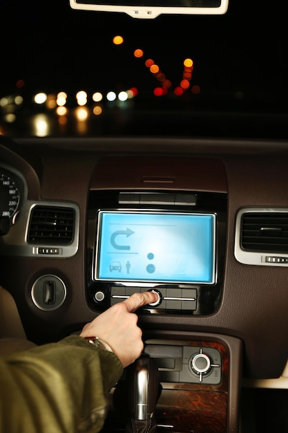 Hombre conduciendo su coche moderno por la noche en el primer plano de la ciudad