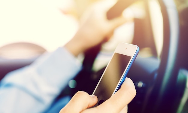 Hombre conductor con smartphone en coche