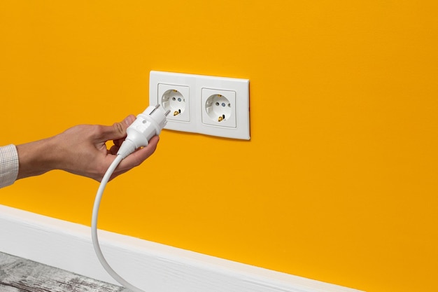 Foto hombre conectando el cable a un enchufe eléctrico