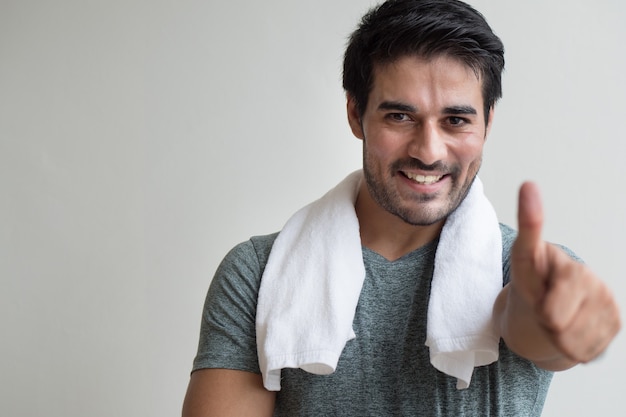 Hombre confiado de la aptitud que señala el pulgar encima del gesto; retrato de un hombre indio feliz, sano y confiado que se ejercita en el gimnasio; asiático, norte de la india, hombre adulto, modelo