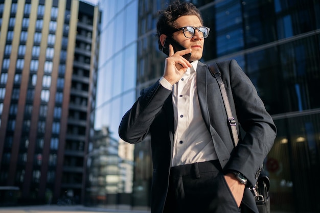 Un hombre confiado hablando por teléfono, un gerente que va a la oficina con un traje de negocios comunicándose