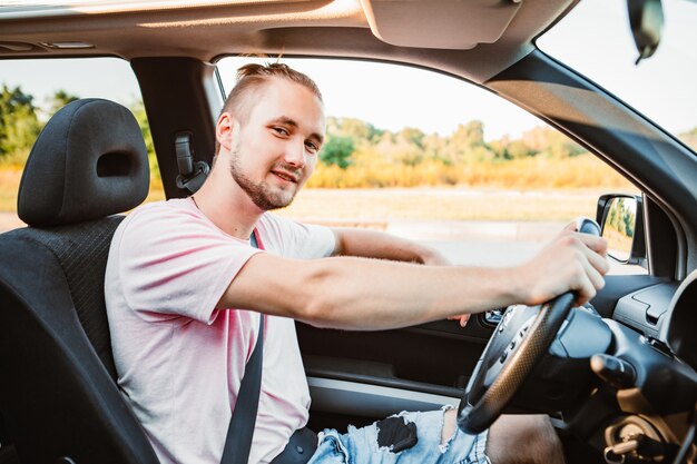 Hombre confiado hermoso joven que conduce el coche. viaje