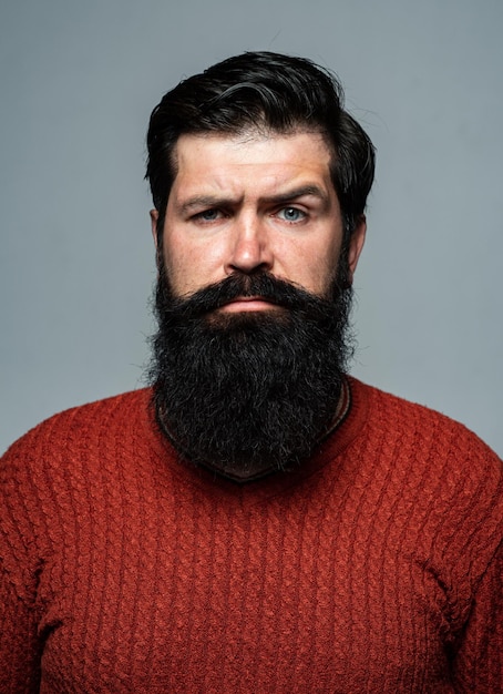 El hombre confiado tiene barba y bigote, parece serio, aislado. Chico serio hipster pensando con expresión mirando. Modelo masculino guapo, primer plano de la cara.