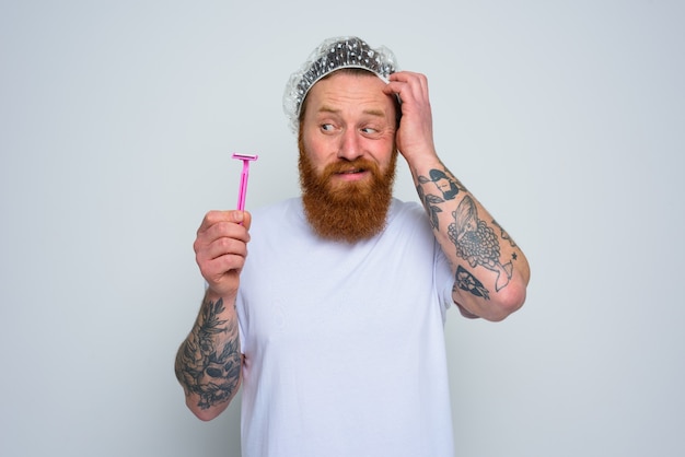 Foto hombre confundido quiere ajustar la barba con una cuchilla de afeitar