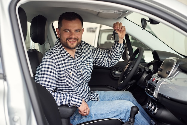 El hombre considera una nueva gama de modelos de automóviles y trata de elegir el mejor para sí mismo.