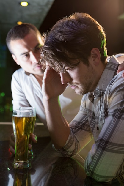 Hombre consolando a su amigo deprimido en el bar