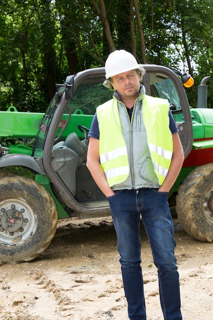 Hombre de la construcción en la máquina industrial excavadora verde