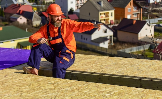 Hombre construir casa Instalación de techo plano fieltro para techos Trabajador de techador en ropa protectora especial nueva