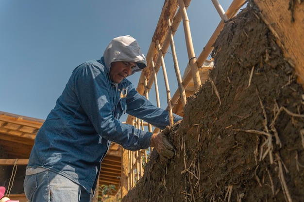 Hombre construyendo un muro con técnicas de bioconstrucción