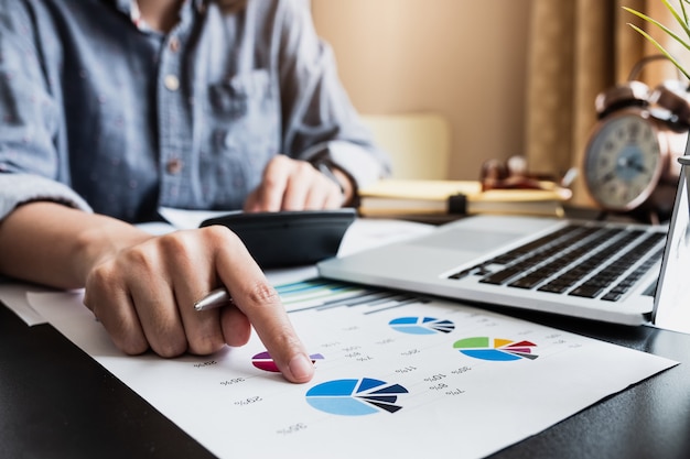 Un hombre consultor de inversiones analizando el informe financiero anual de la compañía, el balance general, trabajando con documentos gráficos.