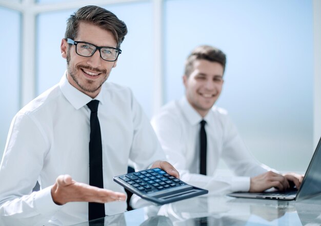 Hombre contando gastos usando calculadora con computadora portátil en aleta de mesa