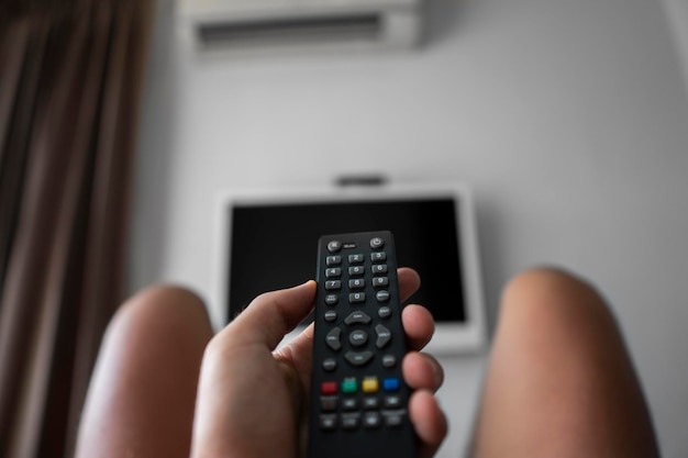 Foto el hombre con control remoto en la mano quiere encender la televisión y presiona el botón del control remoto