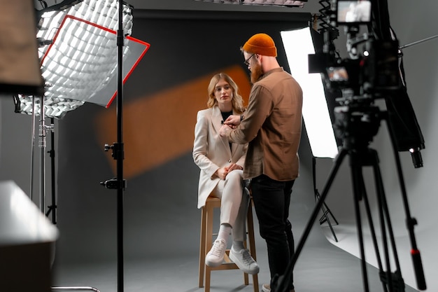 Foto un hombre está conversando con una mujer en un taburete frente a una cámara para una televisión de entretenimiento