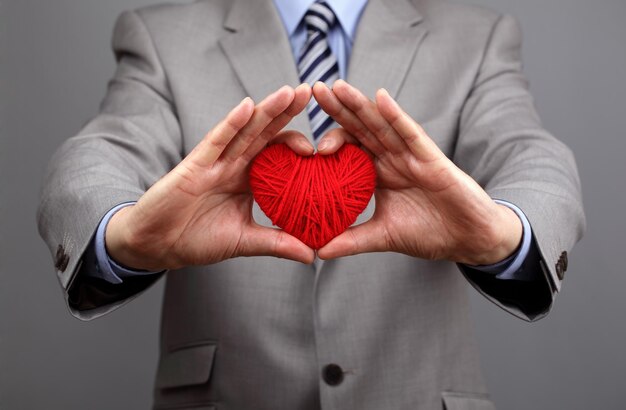 Hombre con un corazón de lana roja concepto para el día de San Valentín negocio atención al cliente caridad responsabilidad social y corporativa