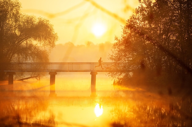 El hombre corre a través del puente al amanecer.