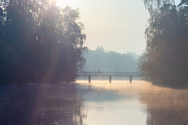 El hombre corre a través del puente al amanecer.