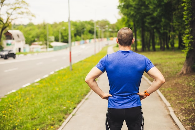 Hombre corredor antes de comenzar a correr mirando en la carretera y preparándose para un entrenamiento duro