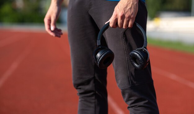 Hombre corredor atlético con auriculares en la pista de atletismo. Espacio para texto