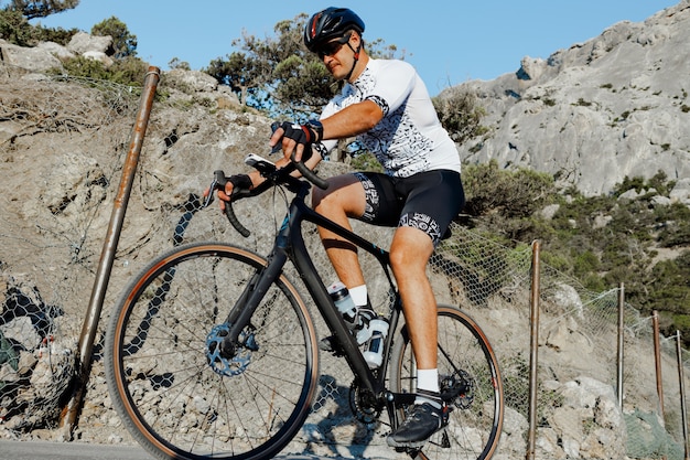 Hombre de corredor de bicicleta de carretera profesional en acción en carretera de montaña