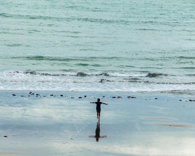 Foto hombre corriendo con los brazos abiertos hacia el mar en luis correa piaui brasil