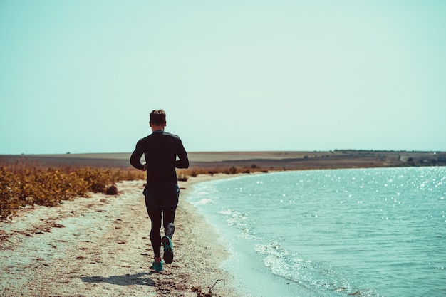 Foto el hombre corriendo por la costa del mar.