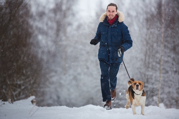 Hombre corriendo con perro beagle en invierno