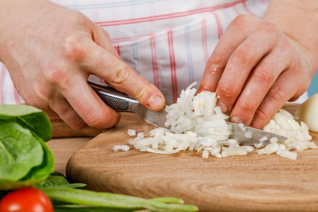 El hombre corta una cebolla blanca con un cuchillo El concepto de cocina