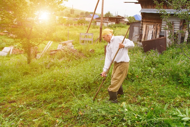 Un hombre corta el césped. vida del pueblo: cosecha de heno para el invierno. la alimentación animal. primer plano de la trenza