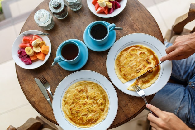 El hombre corta el desayuno de panqueques de plátano en un hotel en Bali