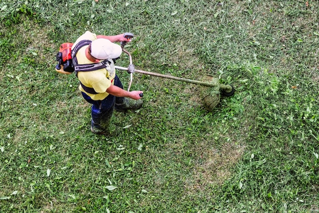 Un hombre corta la hierba en el césped Vista desde arriba Primer plano de un trabajador que corta la hierba