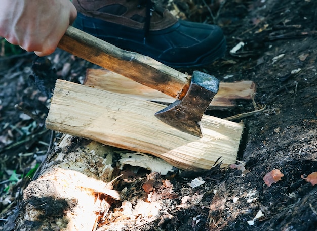 El hombre corta leña al aire libre. Turista en el bosque con un hacha.